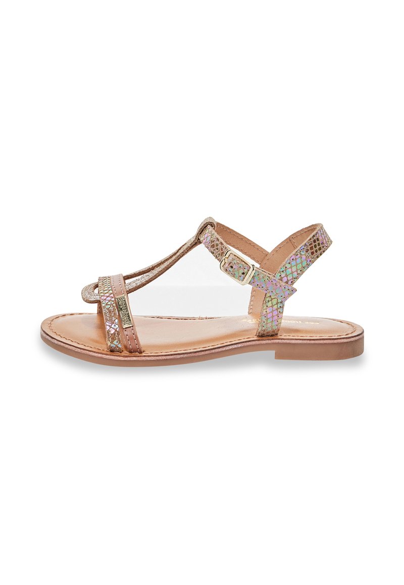 Sandali in pelle color cuoio con cinturini iridescenti, suola piatta e fibbia regolabile alla caviglia. Design con punta aperta e texture liscia.