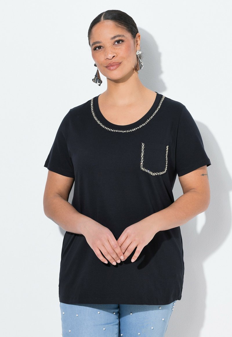 Camiseta negra de manga corta con escote redondo, adornada con tachuelas plateadas en el escote y el bolsillo. Material de algodón suave.