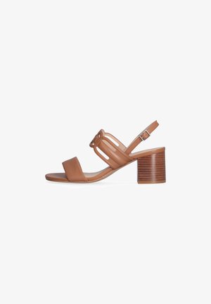 Sandalo con tacco a blocco in pelle marrone, con punta aperta e cinturino alla caviglia regolabile. Presenta un dettaglio annodato e un design con fessure.