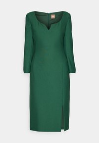 Robe vert foncé longueur genou avec manches longues, encolure crantée, fermeture éclair au dos et fente avant sur le côté gauche.