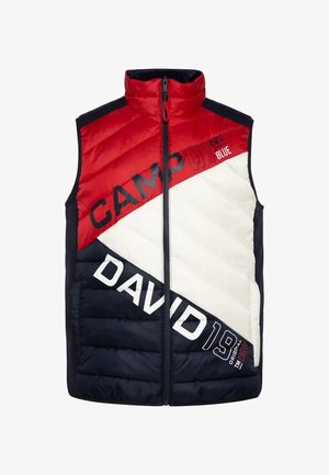 Chaleco sin mangas en rojo, blanco y azul marino, fabricado en material de nailon. Presenta bloques de color en diagonal y grandes gráficos de texto. Cierre frontal con cremallera.