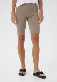 Bež kratke biciklističke hlače od mješavine pamuka, slim fit kroja, s visokim strukom i krojem do koljena. Uparene s crnim ravnim sandalama.