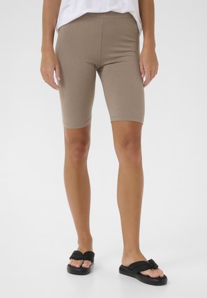 Beige Baumwollmischung Biker-Shorts mit schmaler Passform, hohem Bund und knielangem Schnitt. Kombiniert mit schwarzen flachen Sandalen.