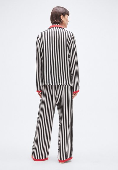 Set de pijamale în dungi alb-negru cu accente roșii, format dintr-o cămașă cu mâneci lungi și pantaloni cu picioare largi, realizat dintr-un material neted.