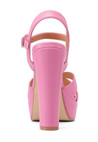 Sandali alti rosa con tacco spesso, dettagli in cinturino e una finitura in ecopelle liscia. La vista posteriore mostra un tacco arrotondato e una fibbia regolabile.
