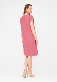 Robe en lin rose à manches courtes, coupe ample, longueur au genou, avec un dos en forme de goutte d'eau et une texture lisse.