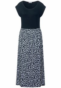 Czarna sukienka z krótkim rękawem, dopasowaną górą i rozkloszowanym dołem w białe, kwiatowe wzory na czarnym tle. Miękka faktura materiału.