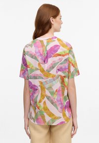 Leichtes Kurzarmoberteil mit einem pinken Hintergrund, verziert mit bunten, abstrakten Blattmustern in Grün, Gelb und Pink.