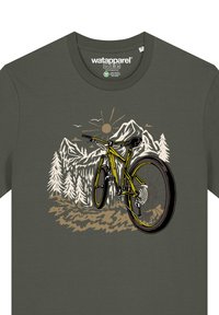 Olivenfarbene T-Shirt mit einer grafischen Illustration eines gelben Fahrrads, Bergen und Bäumen in erdigen Tönen.