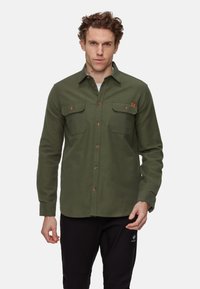 Olijf groene flanellen shirt met lange mouwen, twee borstzakken en bruine knopen. Het materiaal lijkt zacht met een gestructureerde afwerking.