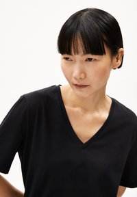 Zwarte v-hals t-shirt met korte mouwen, gemaakt van zachte stof, met een relaxte pasvorm en een gladde textuur. Minimalistisch ontwerp, geen zichtbare patronen.