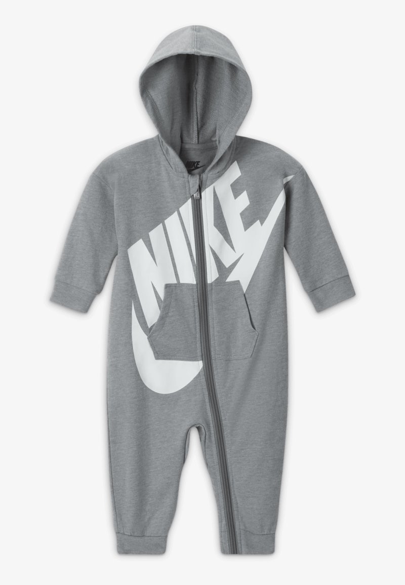 Sivi pametni kombinezon s kapuljačom, s velikim belim Nike logotipom, prednjim zipom i kengurufrontim džepom. Dugi rukavi i manžete na gležnjevima.