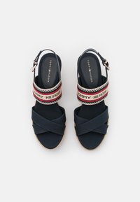 Námořnické modré espadrilky na platformě s křížovými textilními pásky, elastickým páskem s logem a juteovou podrážkou. Nastavitelný pás na kotníku se železnou sponou.