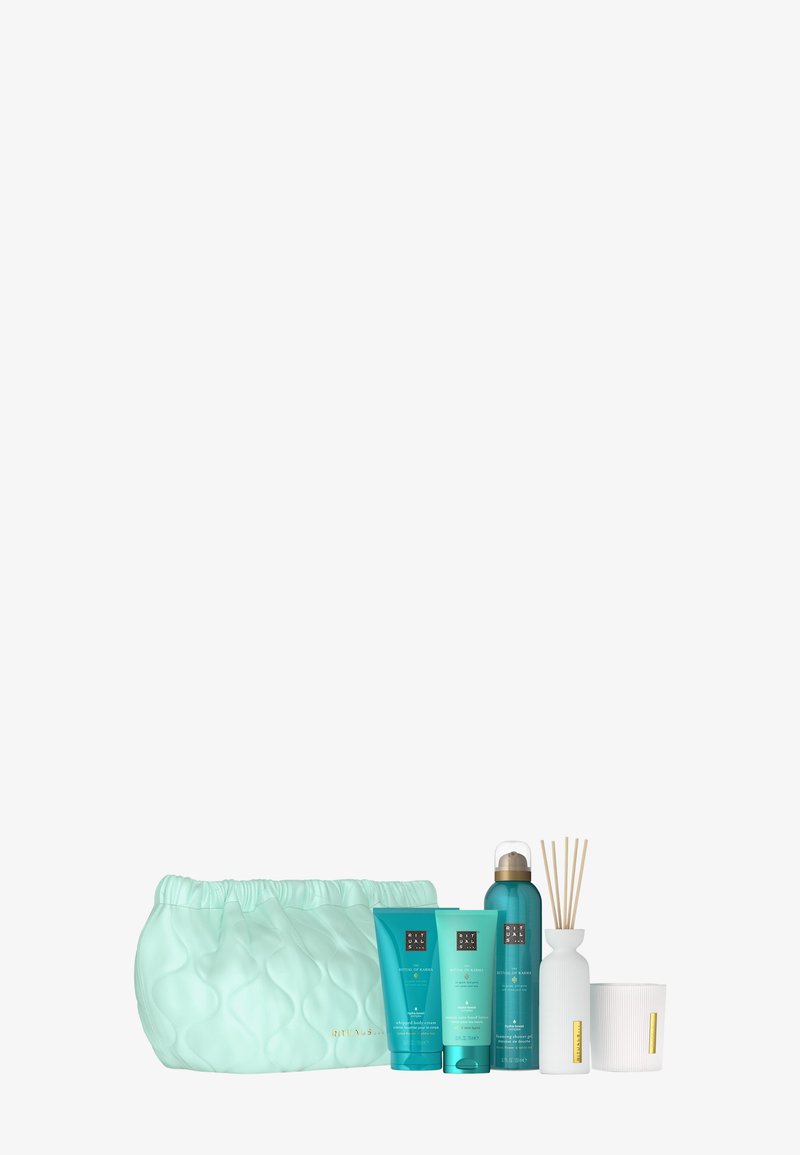 Ljusblå kviltad necessär med fyra blå Rituals hudvårdsprodukter, vit diffuser med pinnar, och vit stearinljus med guld etikett.