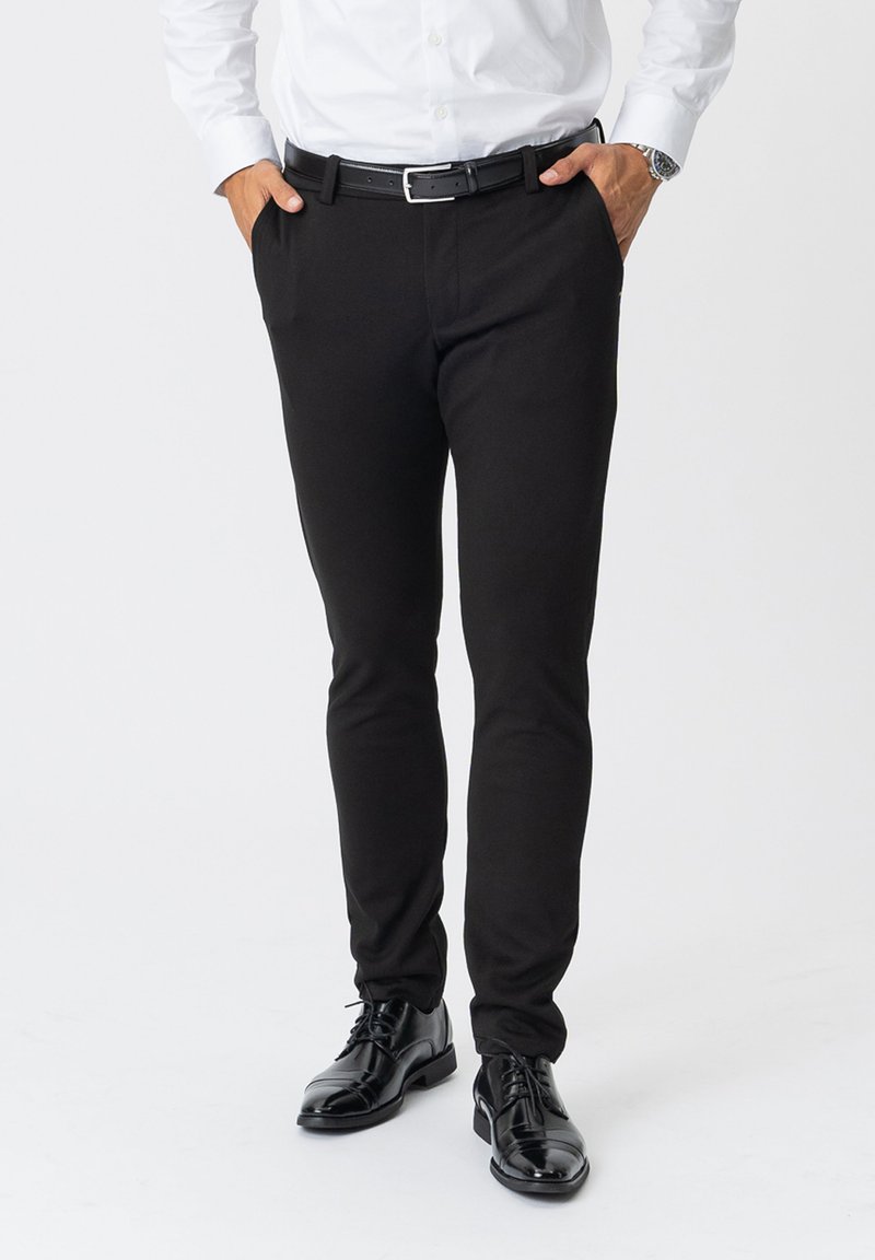 Sorte slim-fit bukser lavet af et glat, strækbart stof, med sidelommer og parret med sorte dress sko.