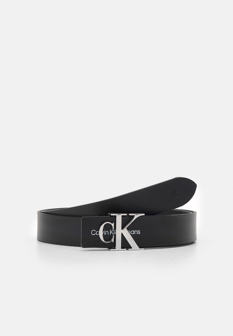 Cintura in pelle nera con una fibbia in metallo argentato con il logo "CK" e il testo stampato "Calvin Klein Jeans" sulla cinghia. Texture liscia.