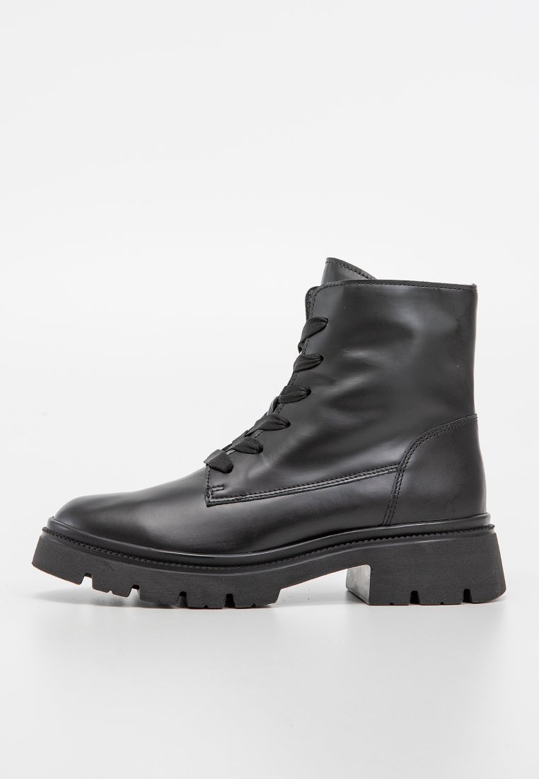 Schwarze Leder-Stiefelette mit dicker Profilsohle und Schnürung, Seitenansicht auf weißem Hintergrund.