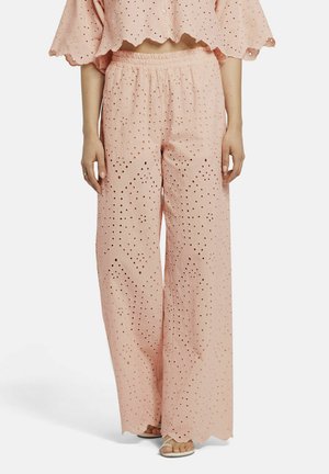 Lichtroze, wijde broek met een gestructureerde stof en uitsnijdingen. Elastische tailleband voor comfort. Vlakke sandalen zichtbaar.