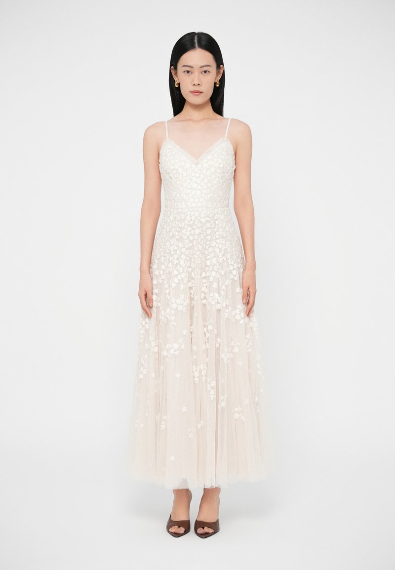 Μάξι φόρεμα σε ανοιχτό μπεζ χρώμα με κεντήματα λουλουδιών στο μπούστο και διαφανές στρωματοποιημένο φόρεμα. Ρυθμιζόμενες λεπτές τιράντες και V-λαιμόκοψη.