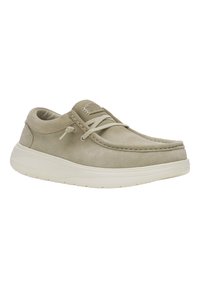 Zapato de ante beige con punta redondeada, suela de goma blanca y diseño de cordones. Presenta detalles cosidos y una etiqueta de marca en la lengüeta.