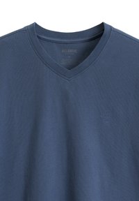 T-shirt w dekoltem w serek w ciemnoniebieskim kolorze, wykonany z miękkiej bawełny, z subtelnym haftowanym logo na piersi. Posiada klasyczny, luźny krój.