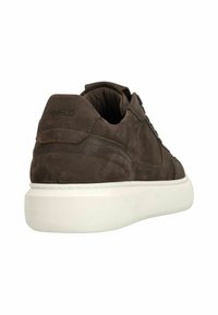 Bruine suede sneaker met een witte rubberen zool, met subtiele stiksels en de woorden "MNFD" in reliëf op de hiel.