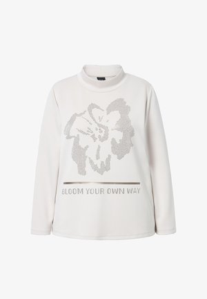 Pitkähihainen, korkean kaula-aukon paita kermansävyssä, jossa on kukkakuosi ja teksti "BLOOM YOUR OWN WAY" hopeanvärisistä napeista edessä. Pehmeä kankaan rakenne.