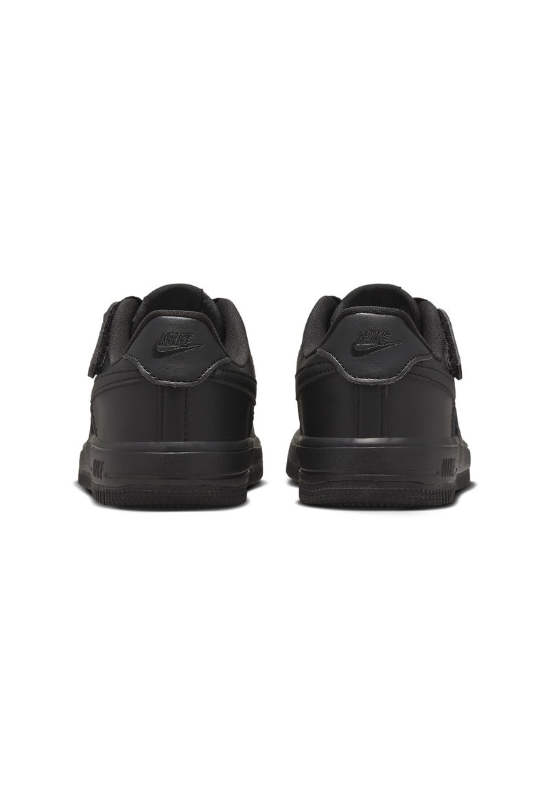 Des baskets Nike noires présentent un matériau synthétique lisse, un design basse, un col rembourré et une semelle en caoutchouc texturée avec des accents de logo.