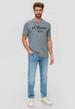 Gray short-sleeve t-shirt with black printed text, paired with light blue jeans and white sneakers. Casual, fitted design.