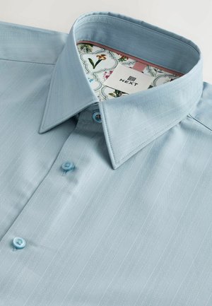 Lichtblauw shirt met een gestreept patroon, voorzien van een puntkraag en twee lichtblauwe knopen. De binnenkant van de kraag heeft een voering van bloemenstof.
