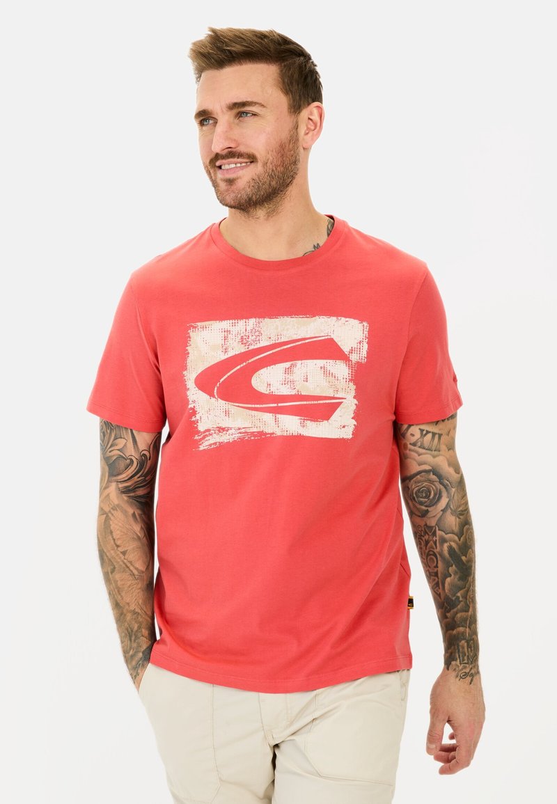 Rød bomulds T-shirt med et hvidt grafisk logo på fronten, korte ærmer og rund hals. Har en afslappet pasform og et logo-tag på siden.