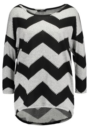 Chemise à manches longues en tissu doux de couleur gris, ornée d'un motif en zigzag noir audacieux, avec un large décolleté et un ourlet légèrement courbé.
