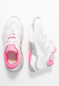 Chaussures de sport blanches avec des accents roses et gris. Tige en mesh, col rembourré et semelle en caoutchouc avec un motif texturé.