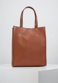 Brązowa torba typu tote ze skóry, z dwoma uchwytami, prostokątnym kształtem, teksturowanym wykończeniem i srebrnymi akcentami metalowymi z przodu jako detal.