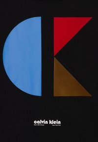 Černá textilie s velkým modrým kruhem, červeným trojúhelníkem a hnědým trojúhelníkem; na spodní části je vytištěný nápis "calvin klein" se detaily města.