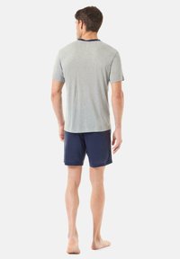 Camisa gris de manga corta con cuello marino, combinada con pantalones cortos marinos. La tela parece ligera y tiene una textura suave.