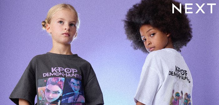 Due bambini indossano t-shirt grafiche oversize. Una è grigia con personaggi colorati del K-pop, l'altra è bianca con un tema simile. Shorts di jeans.
