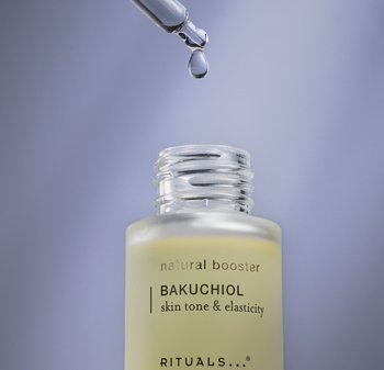 Glasflaske med lys gul væske og en klar pipette. Etiketten læser "naturlig booster BAKUCHIOL hudtone & elasticitet." Sølvdetaljer.