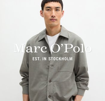 Mężczyzna w jasnoszarej koszuli z guzikami na białej koszulce, stojący na tle jednolitego białego tła.