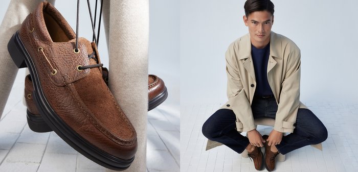 Brązowe zamszowe buty na sznurówki z teksturowanej skóry, złotymi oczkami i czarnymi gumowymi podeszwami; model ma na sobie pasujący strój na jasnym tle.