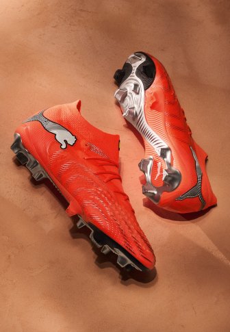 Red football boots with a textured upper, curved shape, and a white Puma logo. Features a silver soleplate with multiple studs for traction.