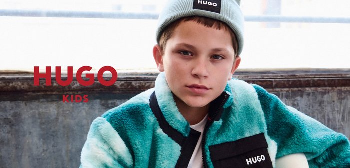 Faux-Fur-Jacke in Türkis und Schwarz mit Reißverschluss, ausgestattet mit einer großen Brusttasche und einer passenden hellblauen Mütze mit Markenlogo.