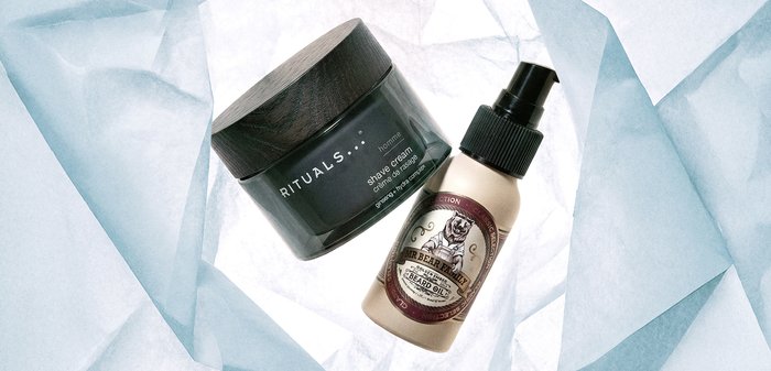 Pot de crème à raser Rituals homme et flacon spray d'huile pour barbe Mr. Bear Family sur fond de papier d'emballage bleu clair froissé.