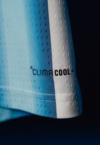 Jasnoniebieska tkanina sportowa z małymi otworami wentylacyjnymi i napisem "ClimaCool" nadrukowanym w pobliżu białego szwu krawędzi.