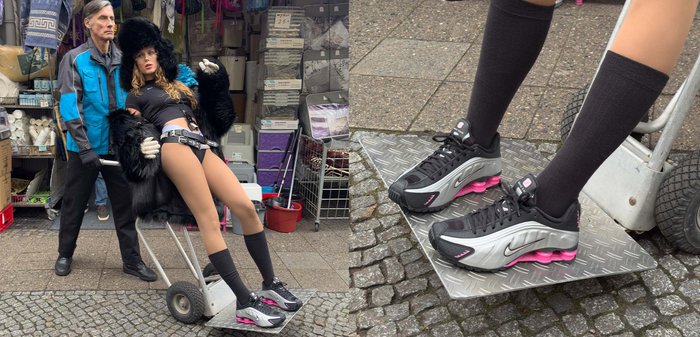 Svart- och grå Nike-sneakers med rosa accenter, gjorda av mesh och gummi; bärs med knähöga svarta strumpor, placerade på en metallisk plattform.