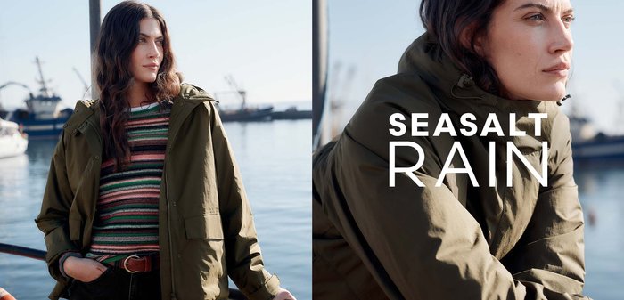 Olivově zelená nepromokavá bunda s kapucí, s předním zipem, velkými kapsami a texturovanou tkaninou. Nositá přes pruhované tričko.