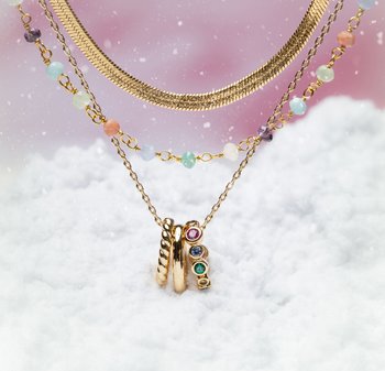 Collane d'oro con pietre multicolori. Presentano una catena intrecciata, maglie delicate e tre anelli con diverse pietre preziose. Ambientate su uno sfondo innevato.