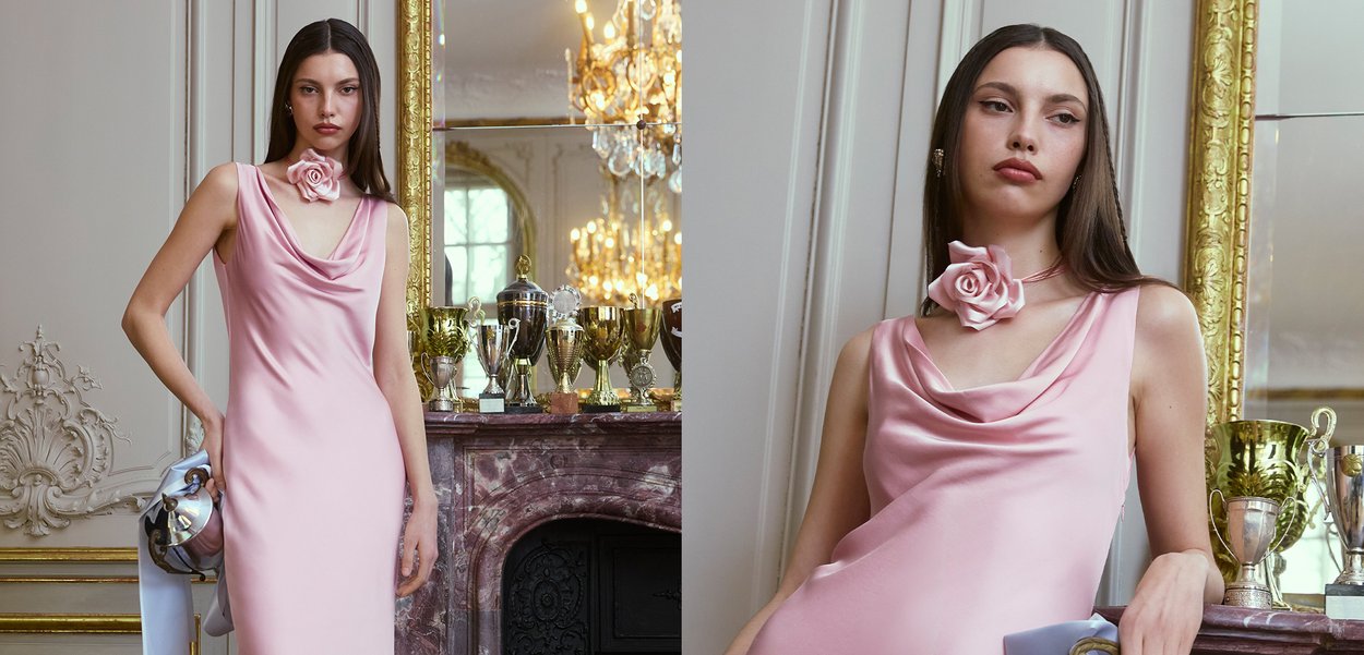 Rosa Satin-Kleid mit einem Cowl-Ausschnitt, versehen mit einem Rosenakzent am Hals. Glatte Textur, figurbetonter Schnitt, mit einer eleganten Silhouette.