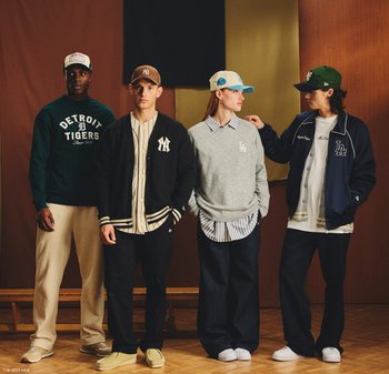 Quattro persone indossano abbigliamento sportivo informale: una felpa verde, un cardigan nero, un maglione grigio sopra una maglietta a righe e una giacca blu navy. Cappelli e pantaloni a taglio rilassato.