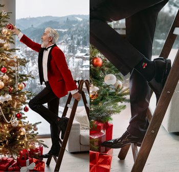 Roter Samtblazer, weißes Hemd und schwarze Hose. Schwarze Schuhe, verzierte Socken mit festlichem Muster. Weihnachtsbaum und eingepackte Geschenke in der Nähe.